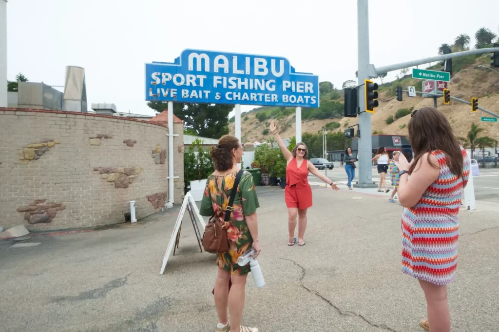 Malibu Pier sign with visitors exploring the entrance to Malibu Sport Fishing Pier in California